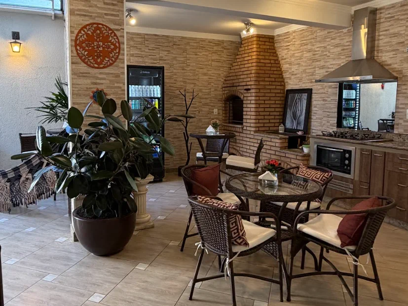 Área de convivência com mesas, plantas e cozinha
